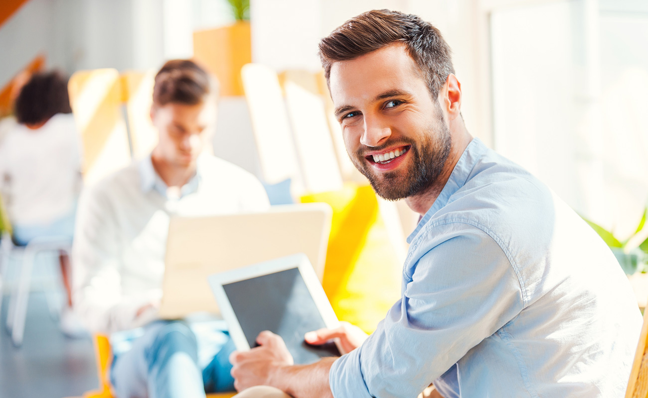 Man on tablet smiling at camera