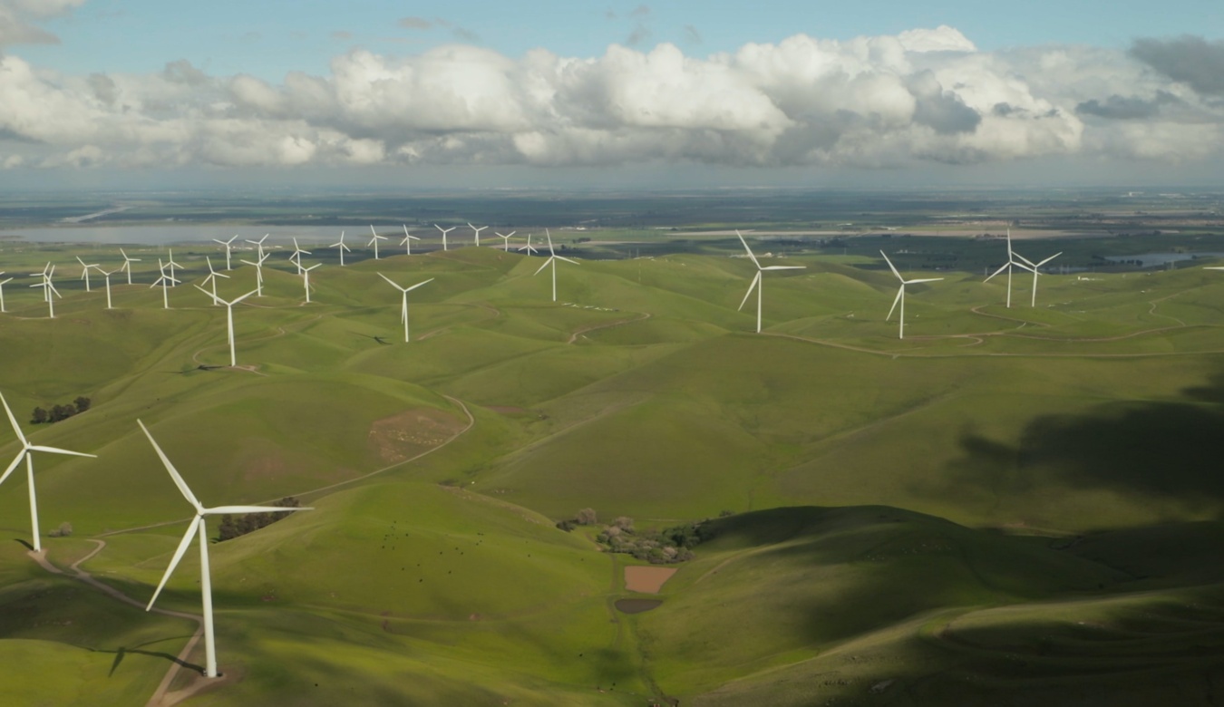 White wind turbines on green hills