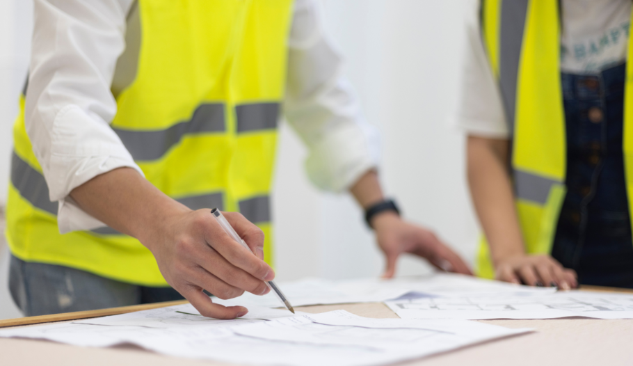 Two people in hi-vis jackets analysing building plans