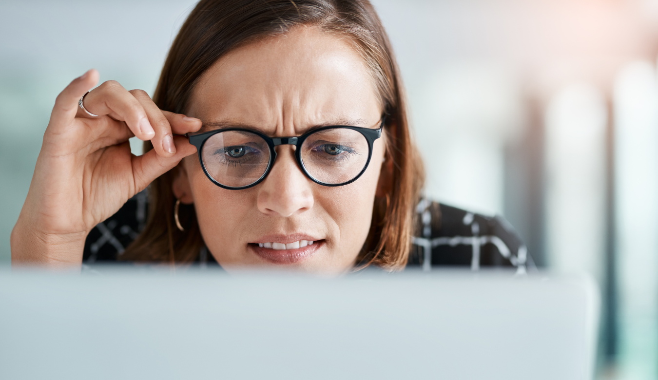 cropped shot of business woman looking closely at laptop confused