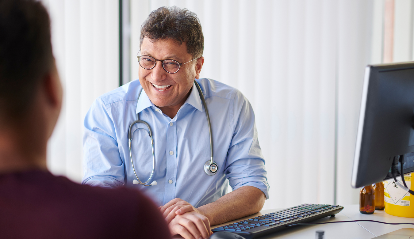 happy gp with stethoscope smiling at patient