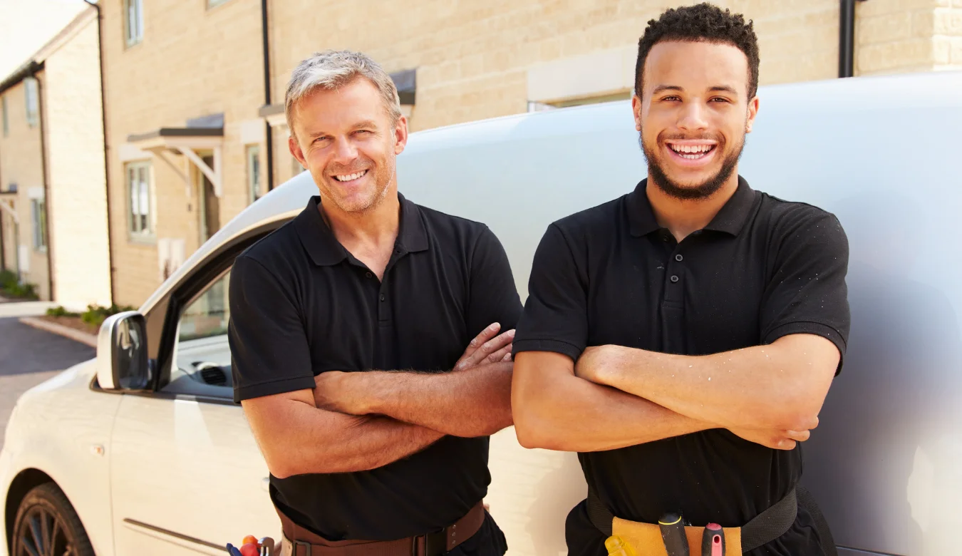 Who tradesmen standing by their white van in front of houses